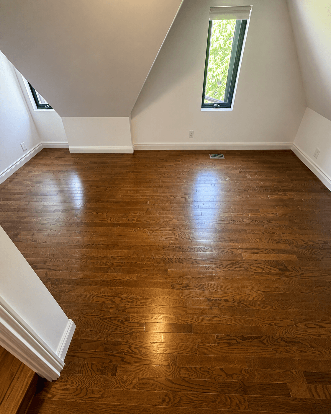 Finished dark hardwood flooring in a bright loft room